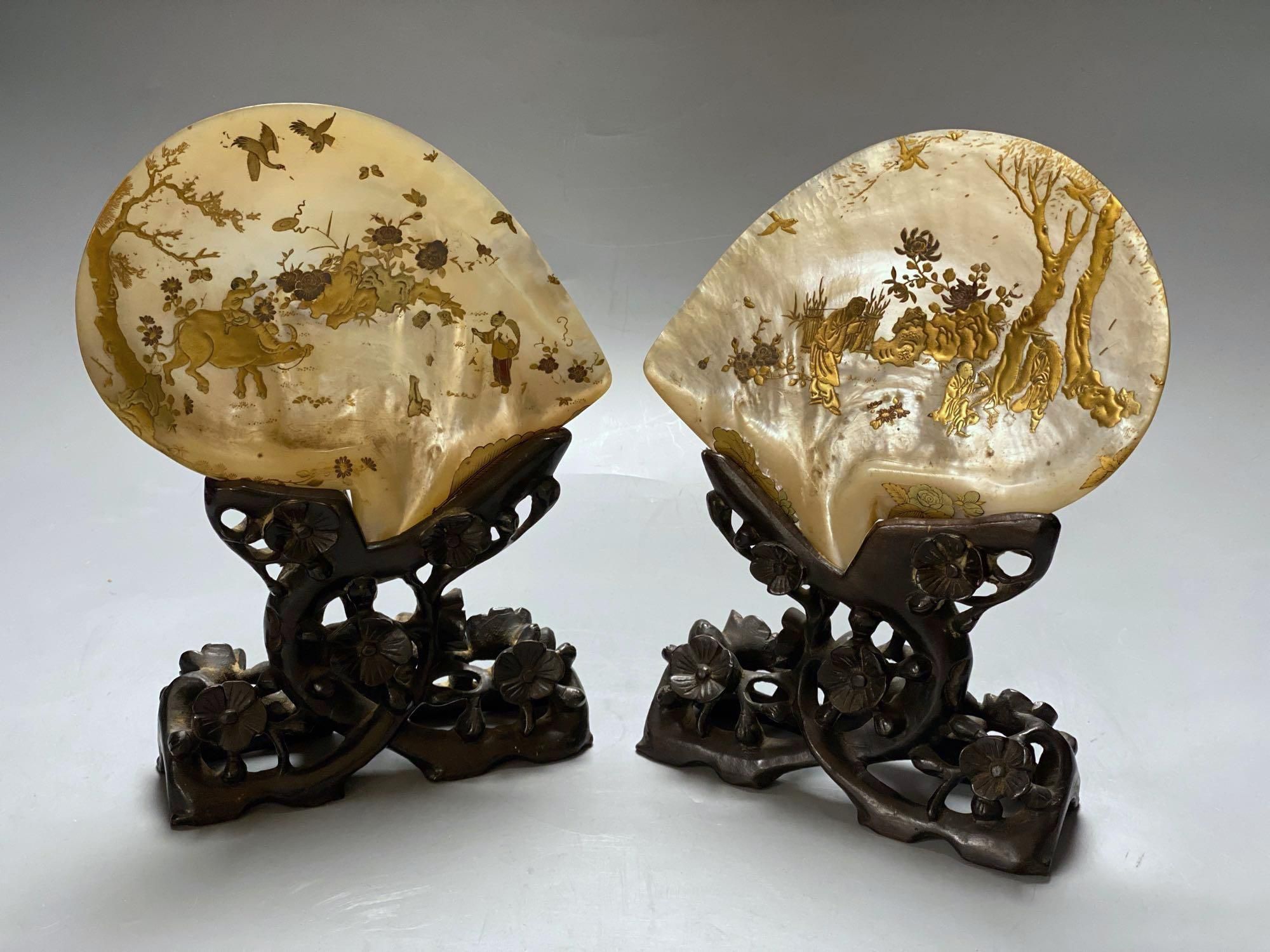 A pair of Chinese mother opearl dishes, gilt lacquered with figures and birds in landscapes, on carved hardwood stand, 26cm